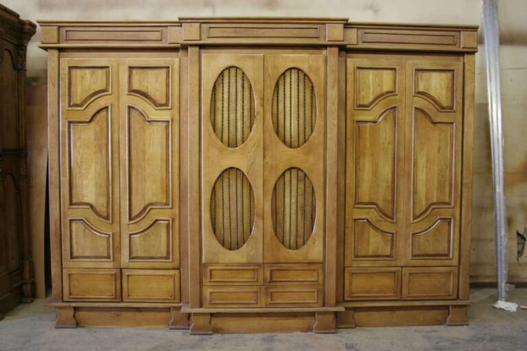 Wide wooden wardrobe with shaped side panels and oval decorative inserts in the centre doors