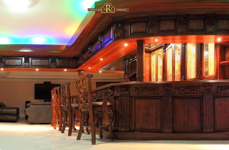 Carved fitted bar with panelled counters, tall stools and illuminated overhead cabinetry