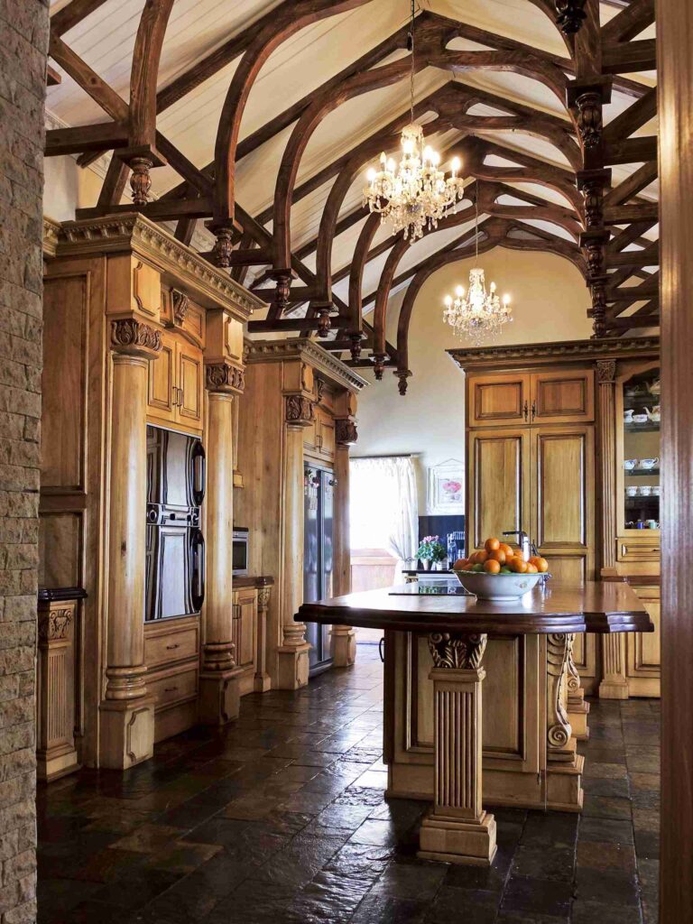 Carved kitchen cabinetry and a central island beneath exposed roof beams