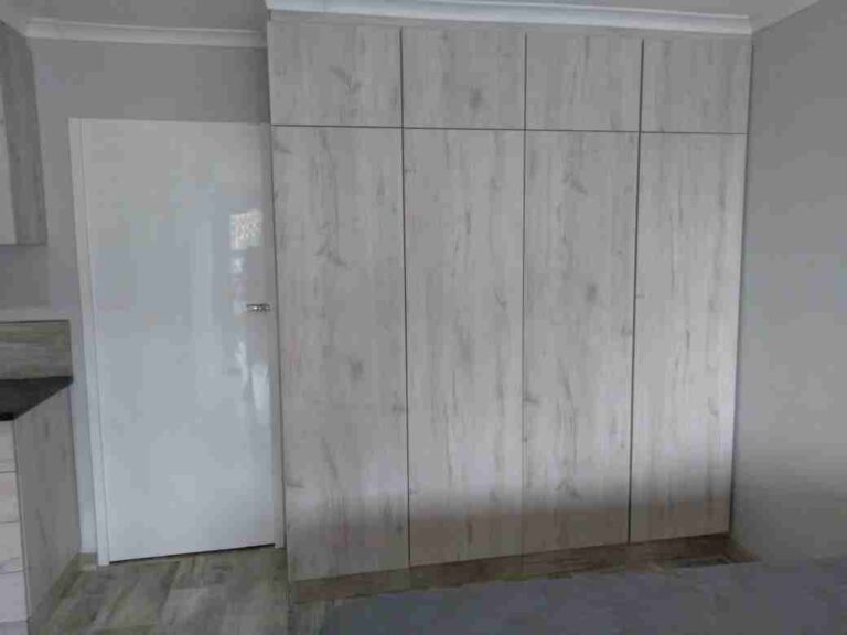 Pale fitted cupboards with tall doors and an upper row of storage doors