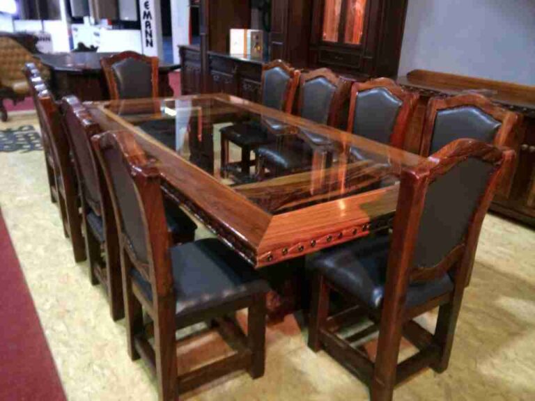 Rectangular wooden dining table with inset glass panels and dark upholstered chairs