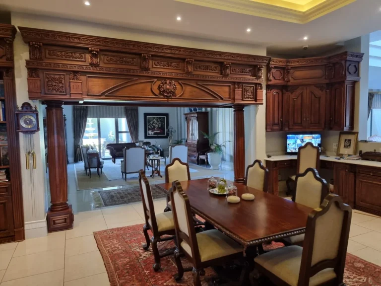 Carved timber archway and fitted corner cabinet beside a dining table and chairs