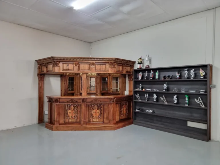 Carved wooden bar beside a dark trophy display cabinet