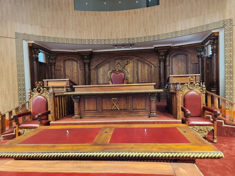 Chamber desk and carved chairs with matching timber panelling at the Senate of Lesotho
