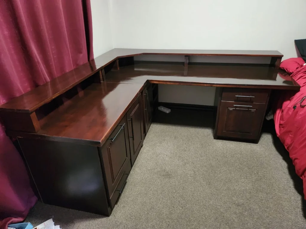 L-shaped wooden desk with raised shelves, drawers and cupboard storage