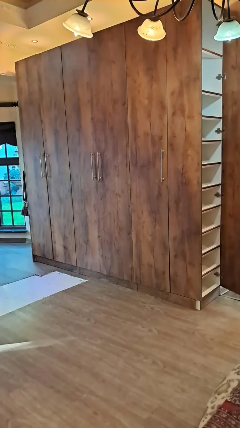 Tall fitted wood-finish wardrobe with one narrow pull-out storage section open