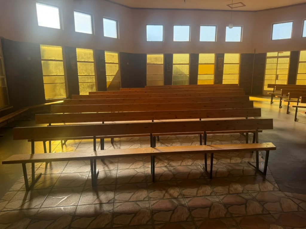 Rows of wooden church benches on dark metal frames inside a worship space